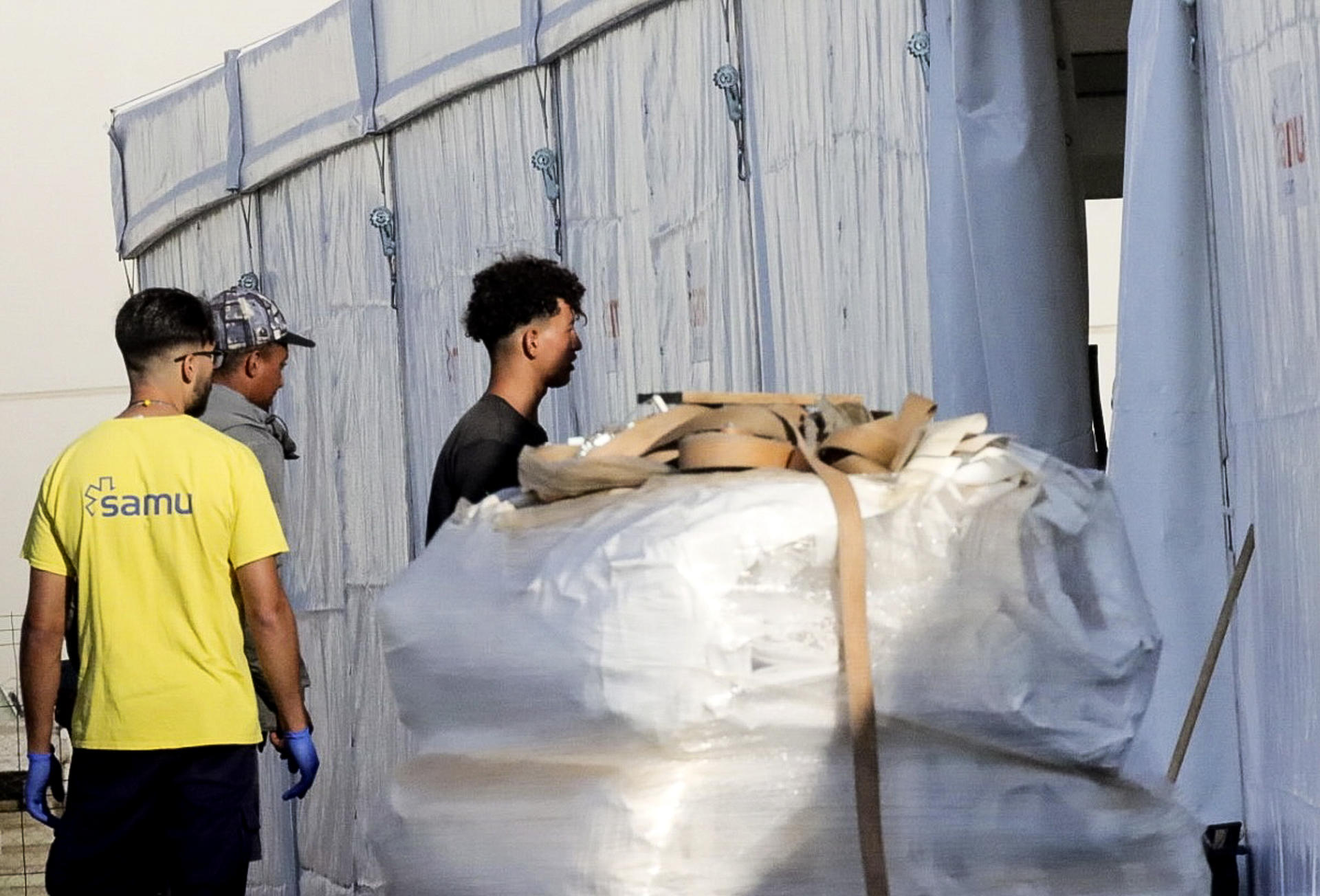 CEUTA, 18/09/2026.- Inmigrantes acceden por el control y registro para de acceder al campamento temporal en muelle Poniente del puerto de Ceuta, este viernes. Las autoridades han iniciado a primera hora de este viernes el traslado de los migrantes asentados en las playas de Benítez y el Trampolín de Ceuta hasta el campamento temporal habilitado en el puerto de la ciudad, con capacidad para unas 1.700 personas. Un amplio dispositivo policial se ha desplegado en torno a las 7:15 de la mañana en ambos asentamientos, donde permanecen adultos y menores desde la entrada masiva registrada el pasado 30 de julio. EFE/Reduan