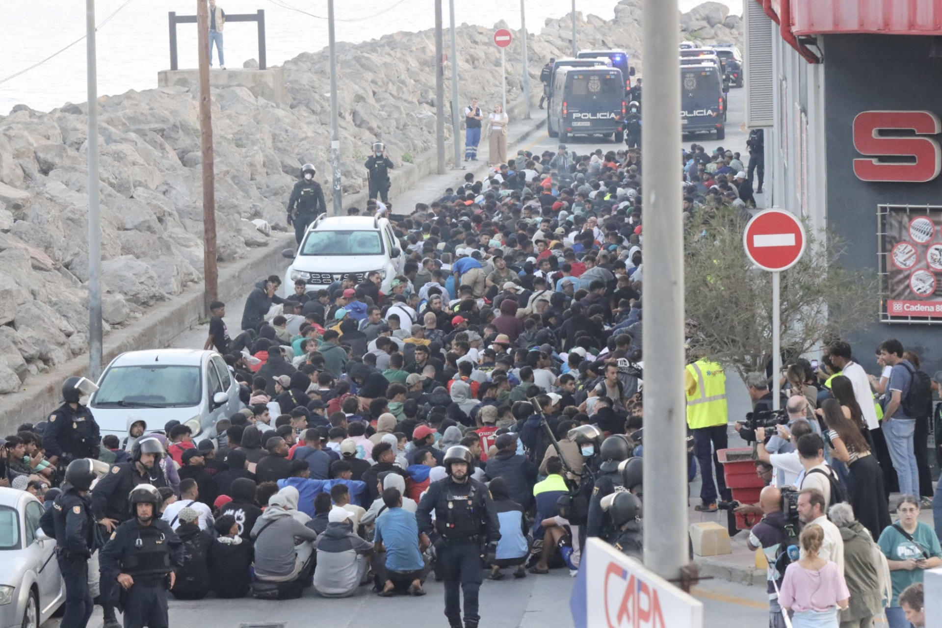 CEUTA, 18/09/2026.- Traslado de migrantes asentados en la playa de Benítez, este viernes. Las autoridades han iniciado a primera hora de este viernes el traslado de los migrantes asentados en las playas de Benítez y el Trampolín de Ceuta hasta el campamento temporal habilitado en el puerto de la ciudad, con capacidad para unas 1.700 personas. Un amplio dispositivo policial se ha desplegado en torno a las 7:15 de la mañana en ambos asentamientos, donde permanecen adultos y menores desde la entrada masiva registrada el pasado 30 de julio. EFE/Reduan