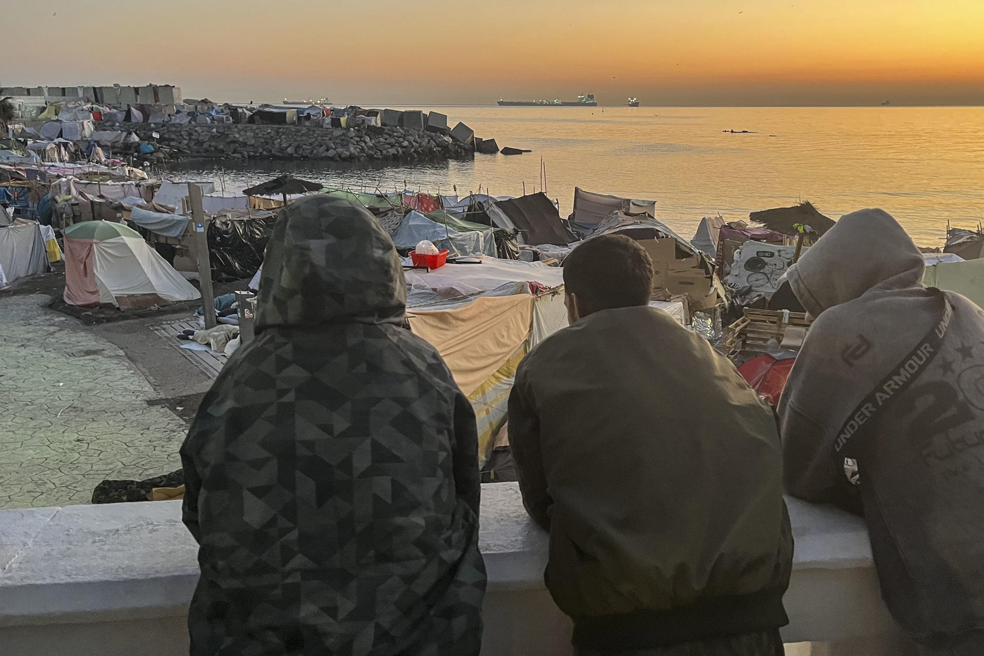 CEUTA (ESPAÑA), 16/09/2026.- Unos migrantes que viven en las chozas de la playa Benítez, a la espera de ser en el nuevo campamento temporal del muelle de Poniente del puerto de Ceuta para migrantes que previsiblemente se inaugura este miércoles. EFE/Reduan