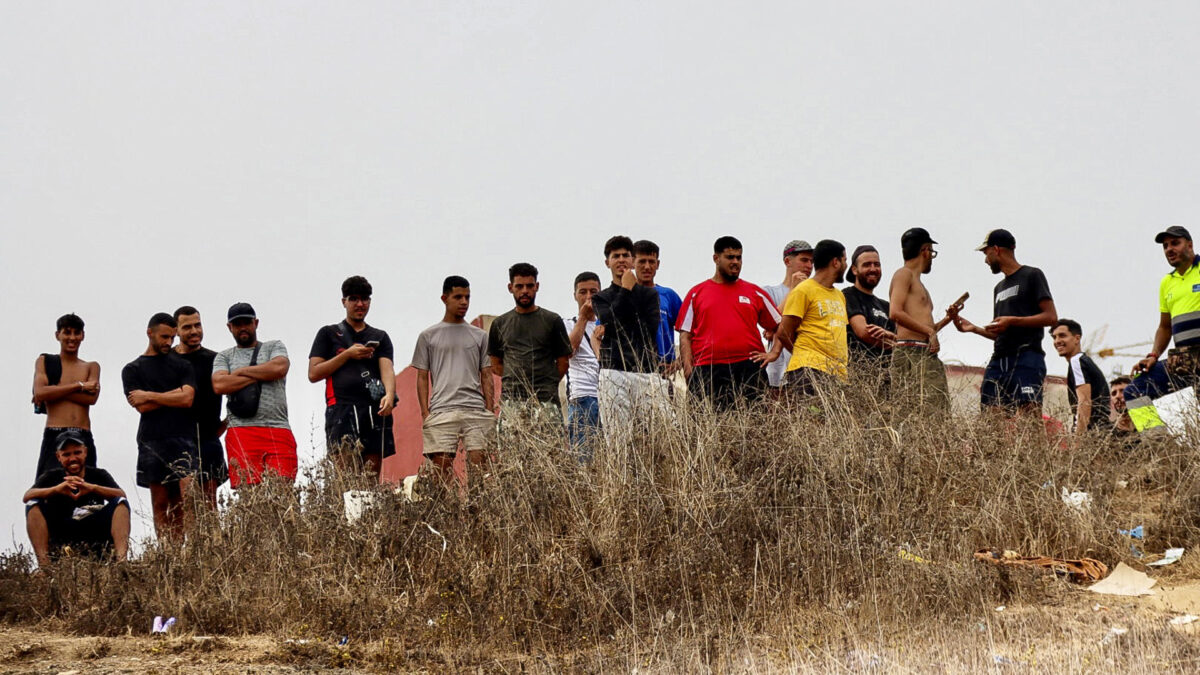CEUTA, 06/09/2026.- Varios migrantes observan desde un monte la multitudinaria protesta en Ceuta para reclamar que se garanticen los derechos de los niños que residen allí, privados en el último mes de numerosas actividades tras la entrada masiva de decenas de miles de migrantes desde Marruecos. EFE/ Reduan