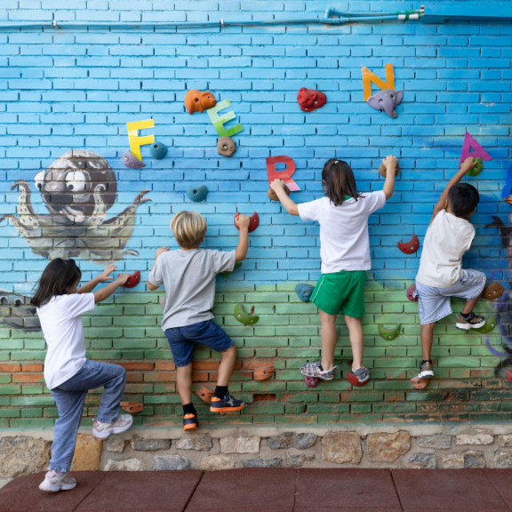 Varios niños escalan en el rocódromo del patio del colegio público Nicolas de las Peñas de Murcia, este martes primer día de clase tras las vacaciones de verano.