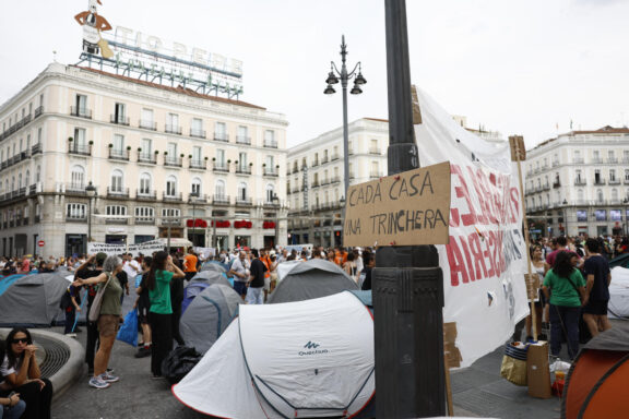 MADRID, 27/09/2026.- Turistas con maletas, gente volviendo de fiesta, personal de la limpieza, otros trabajadores de camino a sus jornadas... Todo eso, como cualquier otro día, está en la Puerta del Sol este domingo al amanecer, pero también cientos de personas acampadas para protestar por la crisis de vivienda. Esta estampa que recuerda tanto al 15-M de 2011 comenzó a orquestarse al final de la manifestación multitudinaria del sábado por la tarde en la capital, que congregó a miles de personas: 25.000, según la Delegación del Gobierno; cerca de 300.000, de acuerdo con el Sindicato de Inquilinas e Inquilinos de Madrid, convocante de la marcha. "Si no nos dejan vivir en Madrid, nos plantamos en su centro", ha reivindicado el Sindicato, que ha logrado movilizar improvisadamente a cientos de personas para ocupar este bajo exterior y muy luminoso de 16.751 metros cuadrados, en una ciudad en la que el precio del alquiler ha subido 60,7 % en los últimos cinco años, según el portal Idealista. EFE/ Rodrigo Jiménez