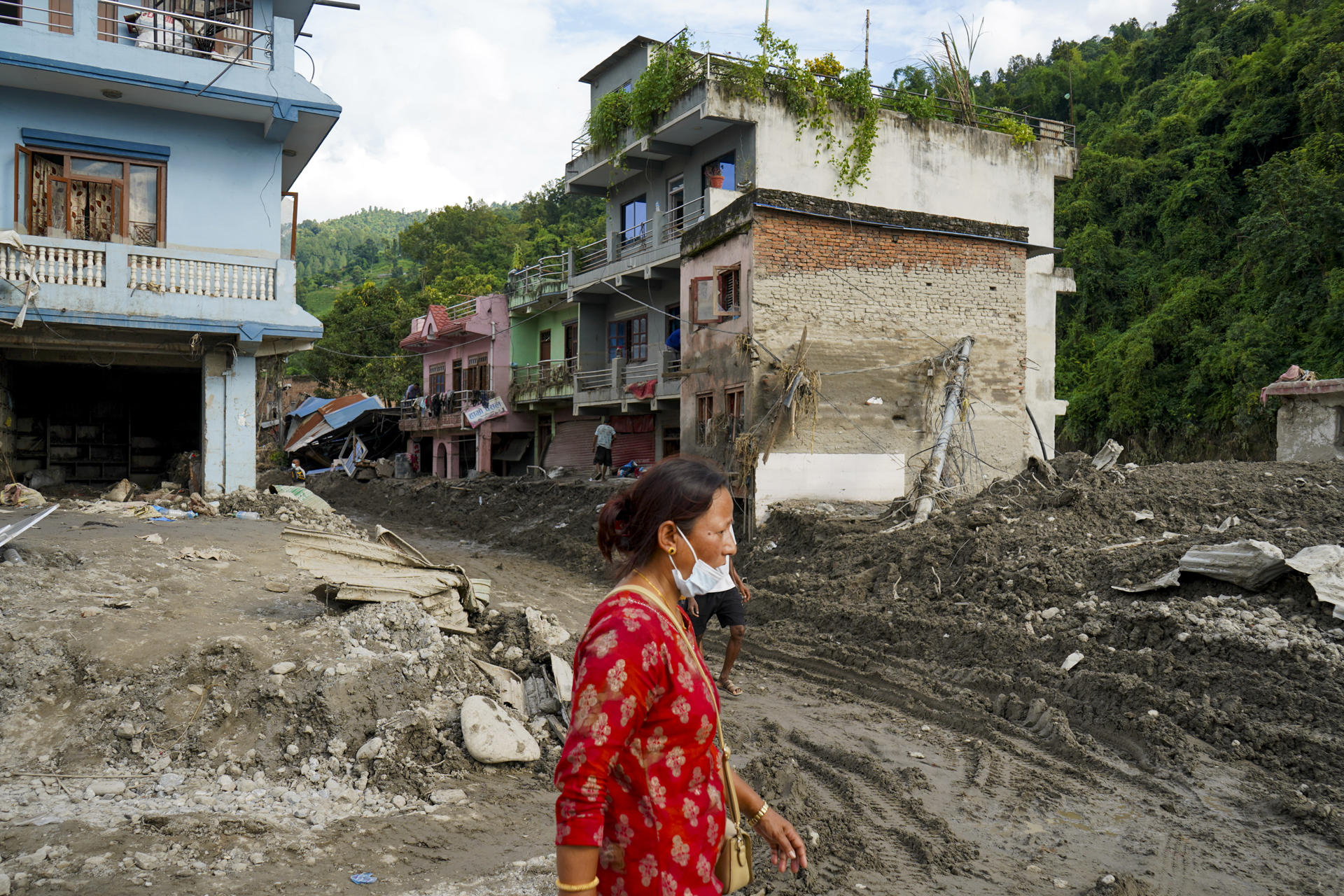 Una mujer camina este lunes por una zona afectada por una riada en Devighat (Nepal). La riada sepultó partes enteras de este pueblo del centro de Nepal bajo varios metros de barro, piedras y escombros, ahora se camina sobre ellos donde antes había calles y, en algunos tramos, los tejados de las casas quedan prácticamente a la altura de los pies. EFE/ Lucía Goñi