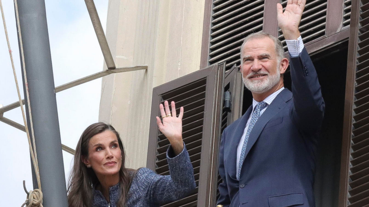 El rey Felipe VI (d) y la reina Letizia (i) saludan desde el balcón del Ayuntamiento.