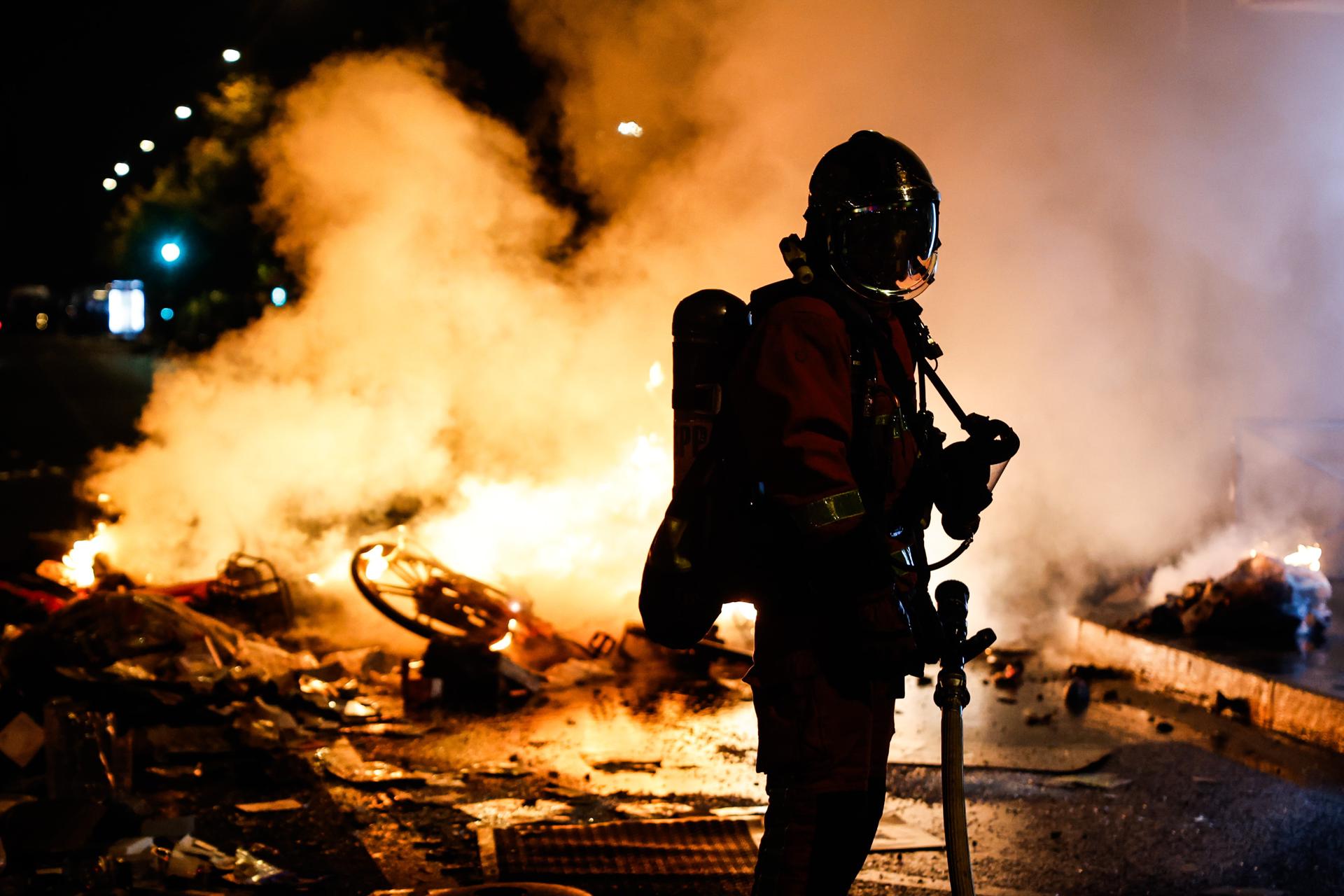 PARIS (France), 19/10/2026.- A French firefighter responds to a street barricade burns as clashes between riot police and demonstrators continue for the second day during nationwide protests against the high cost of living in Paris, France, 18 October 2026. (Protestas, Francia) EFE/EPA/MOHAMMED BADRA