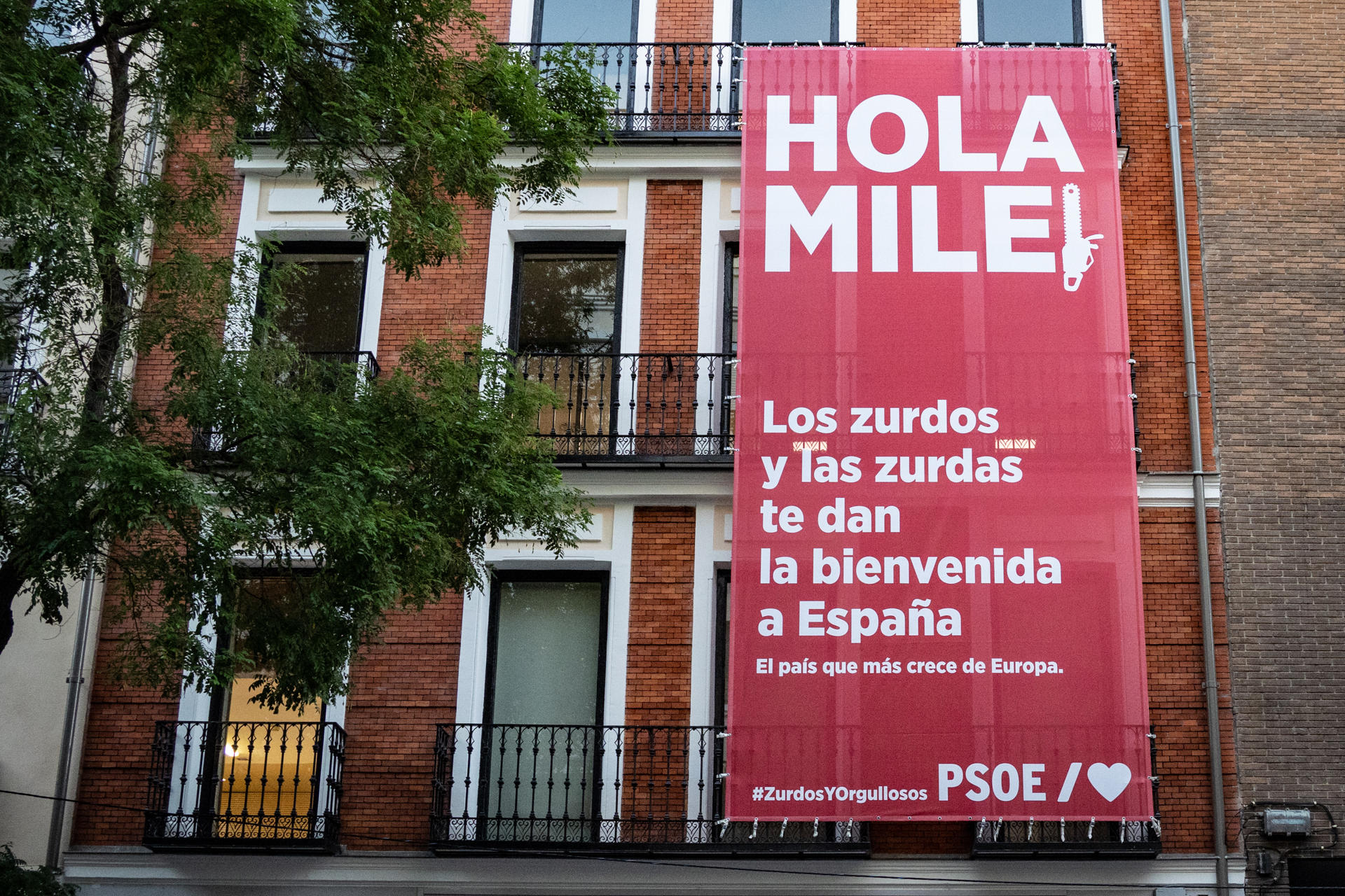 MADRID (ESPAÑA), 21/10/2026.- El PSOE ha desplegado una lona en la fachada de su sede madrileña de la calle de Ferraz para recibir al presidente de Argentina, Javier Milei, de visita en España, en la que los socialistas muestran su orgullo de ser "zurdos". "Hola Milei. Los zurdos y las zurdas te dan la bienvenida a España. El país que más crece de Europa", se puede leer en letras blancas y fondo rojo, donde la segunda 'i' del apellido del mandatario tiene forma de motosierra. EFE/PSOE - SOLO USO EDITORIAL/SOLO DISPONIBLE PARA ILUSTRAR LA NOTICIA QUE ACOMPAÑA (CRÉDITO OBLIGATORIO)