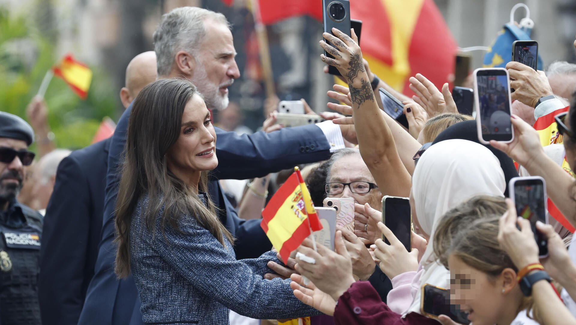 CEUTA, 13/10/2026.- El rey Felipe VI (i, atrás) y la reina Letizia (i, en primer término) saludan a la multitud que espera su llegada ante el Ayuntamiento de CEuta, este martes. Los reyes han aterrizado este martes en el helipuerto de Ceuta donde a las 12:30 comenzarán su agenda de actos de esta visita histórica, la primera que realizan a la ciudad, para expresar su apoyo a los ceutíes tras la entrada masiva de migrantes a finales del pasado mes de julio. EFE/Chema Moya