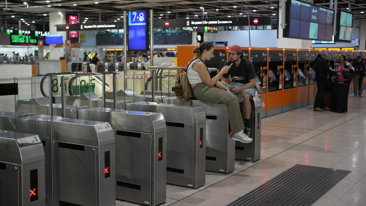 BARCELONA (ESPAÑA), 04/10/2026.- Dos pasajeros esperan la salida de su tren de Rodalies en la estación de Sants, en Barcelona este domingo. Rodalies ha anunciado que los trenes del servicio ferroviario de cercanías y media distancia sigue suspendido en Cataluña hasta nuevo aviso como consecuencia de la situación meteorológica, con excepción de las líneas RL3, RL4 y R16. EFE/ Alejandro García