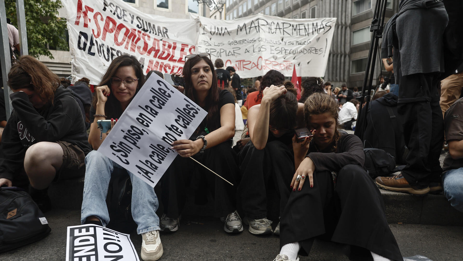 MADRID, 02/10/2026.- Los manifestantes en el exterior del Congreso de los Diputados siguen en sus móviles la votación de los dos decretos sobre vivienda. Centenares de acampados en la Puerta del Sol en demanda de medidas para hacer frente a la crisis de la vivienda se han concentrado a las inmediaciones del Congreso de los Diputados de cara al debate y la votación de los dos decretos sobre vivienda que previsiblemente serán rechazados este viernes por la Cámara Baja. EFE/Sergio Pérez