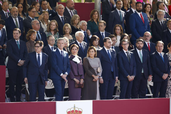 MADRID, 12/10/2026.- Los presidentes autonómicos de (de i a d) Cataluña, Salvador Illa; Galicia, Alfonso Rueda junto a su mujer, Marta Coloret; de Cantabria, María José Sáenz de Buruaga; de Asturias, Adrián Barbón; La Rioja, Gonzalo Capellán; Murcia, Fernando López Miras, y Valencia, Juan Francisco Pérez Llorca, durante el tradicional desfile militar por las calles del centro de Madrid en el que participan casi 4.400 militares, 144 vehículos, 39 motos, 50 aviones y 32 helicópteros, este lunes Día de la Fiesta Nacional.