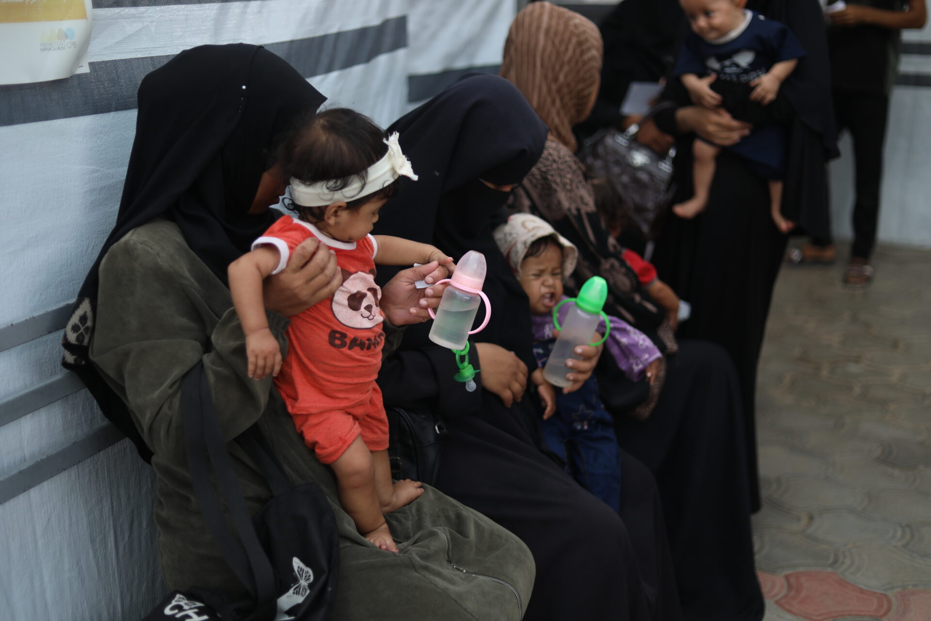 Eight-month-old Janna Abu-Mesbeh, who suffers from severe malnutrition, waits for consultation while her mother gives her a bottle of water. "She only sleeps after drinking water, pretending it’s milk. There’s nothing else to give her." Saja Mansour Awda Abu Dagga.