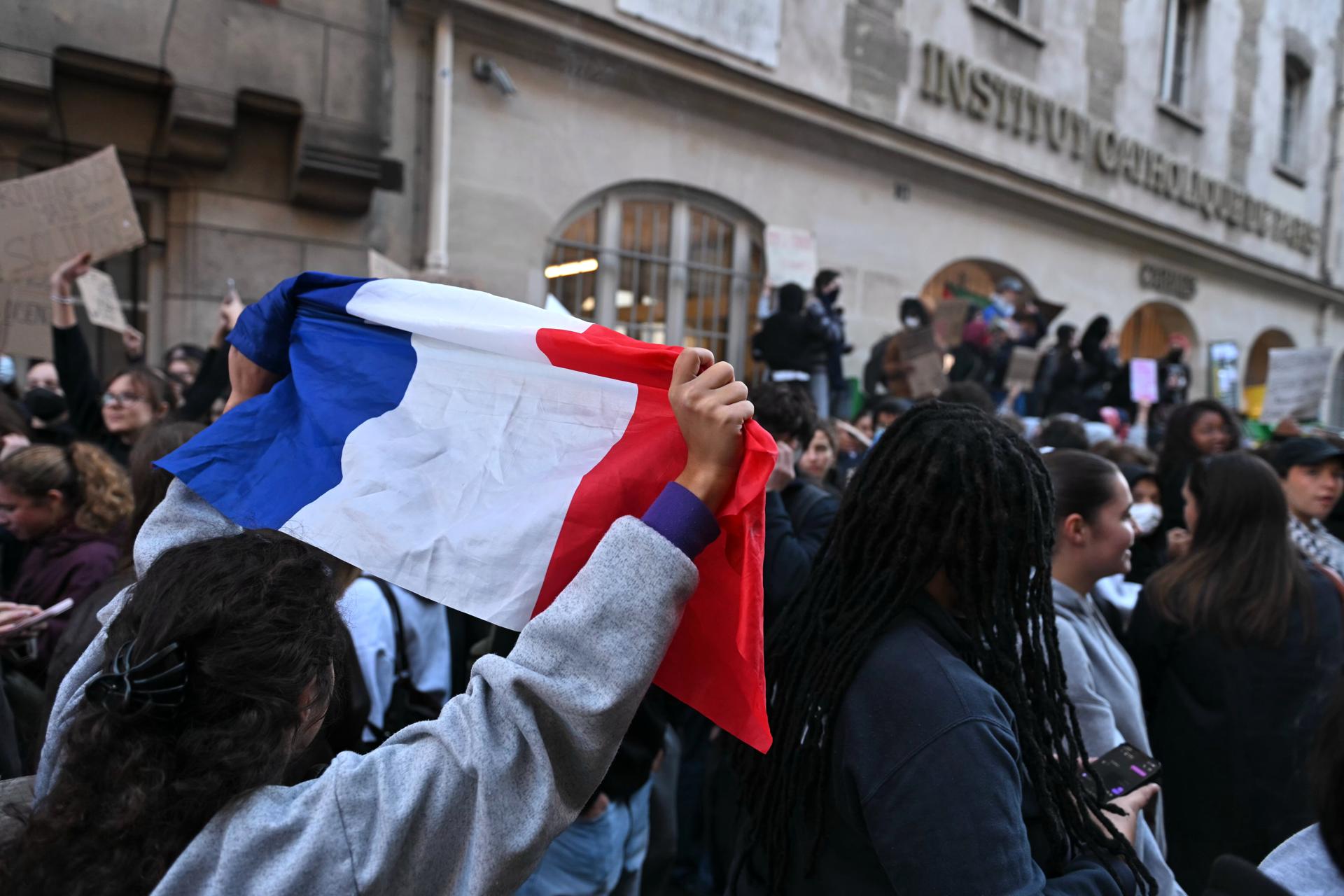 PARIS (France), 08/10/2026.- A student holds up a French national flag while demonstrating outside the Carmes campus of the Institut Catholique de Paris (ICP), in Paris, France, 08 October 2026. A wave of nationwide protests by high school students has been sweeping across France since late September 2026, later joined by university students, over severe teacher shortages, overcrowded lecture halls and classrooms, resource deficits, and poor learning conditions. (Protestas, Francia) EFE/EPA/FIRAS ALTOUKHI