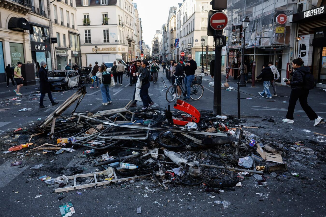 Paris (France), 18/10/2026.- People walk past remains of a street bonfire in the aftermath of clashes between riot police and demonstrators in Paris, France, during nationwide protests against the high cost of living in the country, 18 October 2026. (Protestas, Francia) EFE/EPA/MOHAMMED BADRA